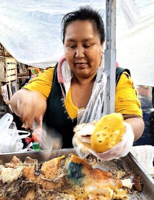 Vendedora de sandwiches de cerdo en la puerta de una de las naves. Foto, Rodolfo Reich.